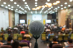 Microphone over the Abstract blurred photo of conference hall or