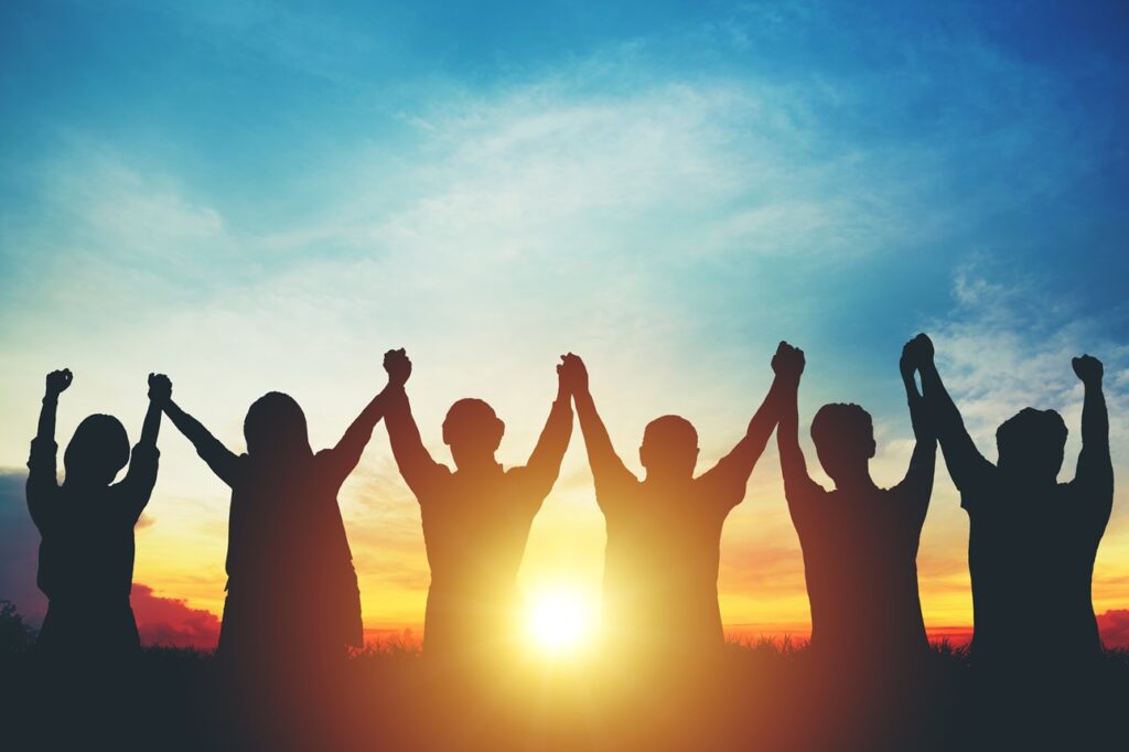 Silhouette of group business team making high hands over head in sunset sky