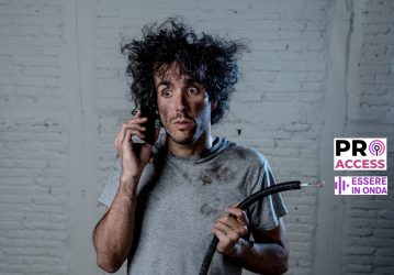 Portrait of young man holding electrical cable after domestic accident with dirty burnt funny face expression calling desperate with mobile phone asking for help. Electricity repairs and DIY concept.