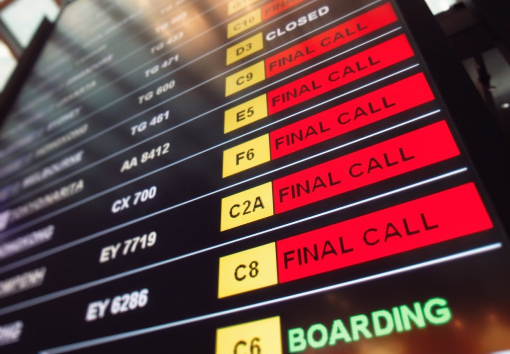 Many red sign final call flights on the departure table of an airport