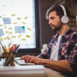 Creative businessman using computer while listening music