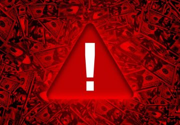 Global Economy Red danger warning sign on bunch of hundred dollar bills