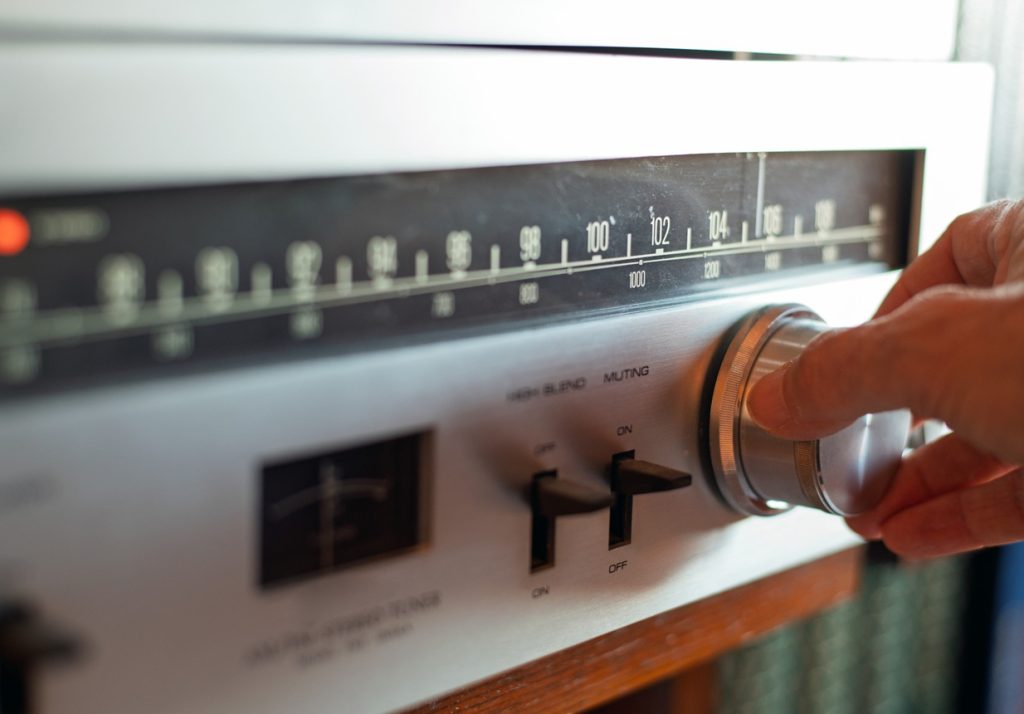 Hand Turning Knob On Vintage Analog FM Radio Tuner With Retro Dial And Controls