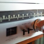 Hand Turning Knob On Vintage Analog FM Radio Tuner With Retro Dial And Controls