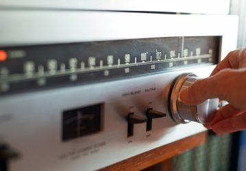 Hand Turning Knob On Vintage Analog FM Radio Tuner With Retro Dial And Controls