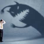 Business man afraid of his own shadow monster concept