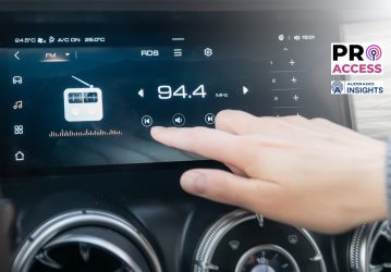 The passenger controls the radio on the car's touchscreen with his finger. An individual adjusts the radio on a sleek car dashboard touchscreen, highlighting convenience and technology.