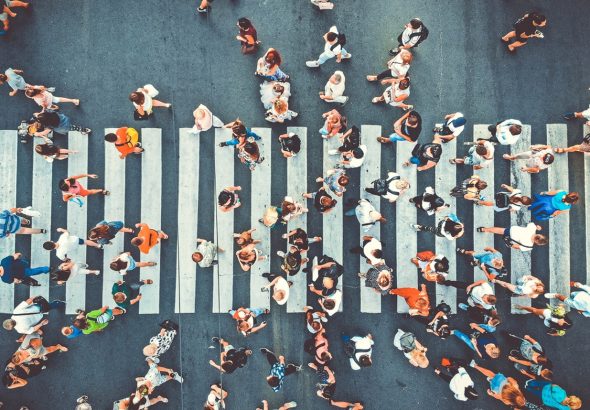 Aerial. People crowd on pedestrian crosswalk. Top view background. Toned image.