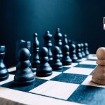 A single white pawn stands against an entire board of black chess pieces. Representative of a one man army/business leader standing against the competition - with room for text